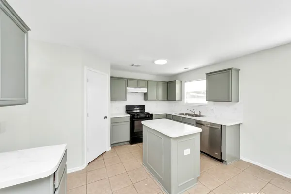 a kitchen with a sink a stove top oven a washer dryer and white cabinets