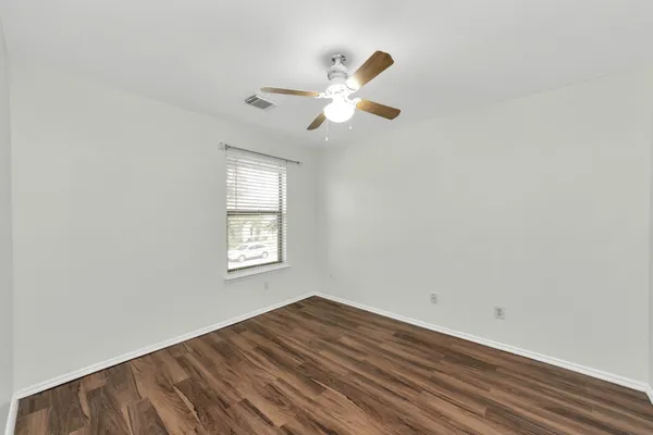 a view of empty room with wooden floor and fan
