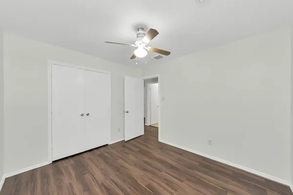 a view of a room with wooden floor and a ceiling fan