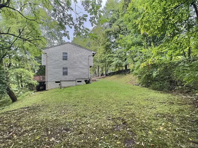 a backyard of a house with plants and large tree
