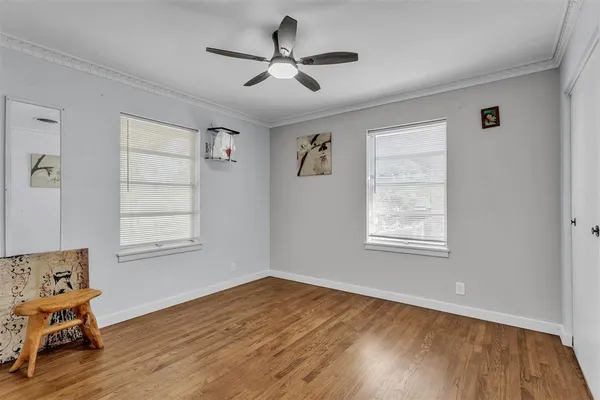 a view of a room with wooden floor ceiling fan and windows