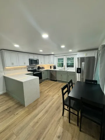 a living room with stainless steel appliances furniture and a flat screen tv