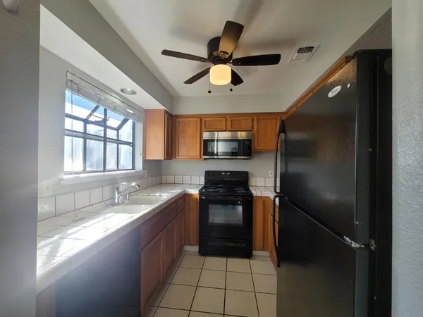 a kitchen with stainless steel appliances granite countertop a sink a stove a refrigerator a washer dryer and white cabinets