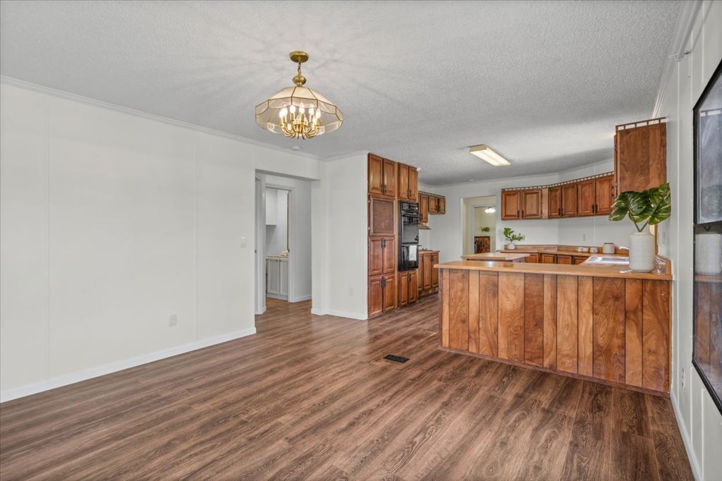 13501 Nutty Brown Road, Unit B Austin, TX 78737 - Photo 15 of 29 Natural wood cabinets and durable plank flooring define this inviting kitchen and adjacent dining area.