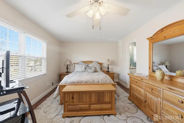 a spacious bedroom with a bed a dresser and potted plant on the dresser