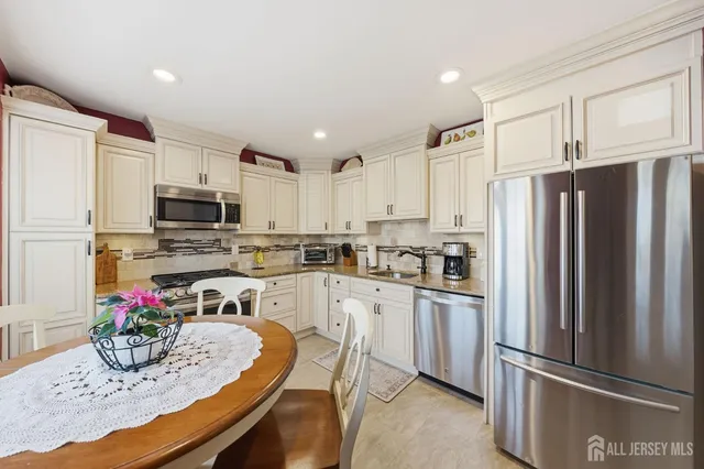 a kitchen with granite countertop stainless steel appliances a refrigerator sink cabinets dining table and chairs