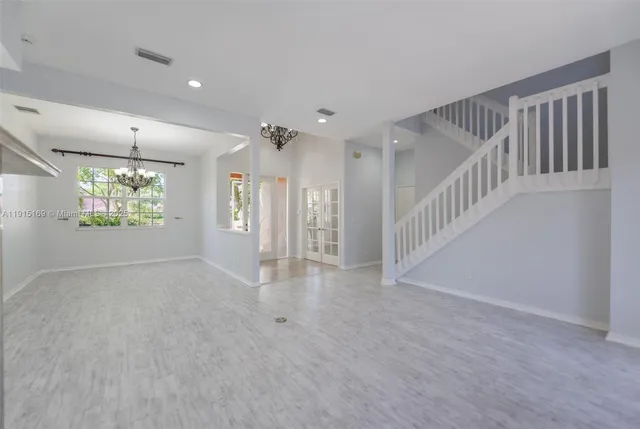 a view of an empty room with chandelier fan