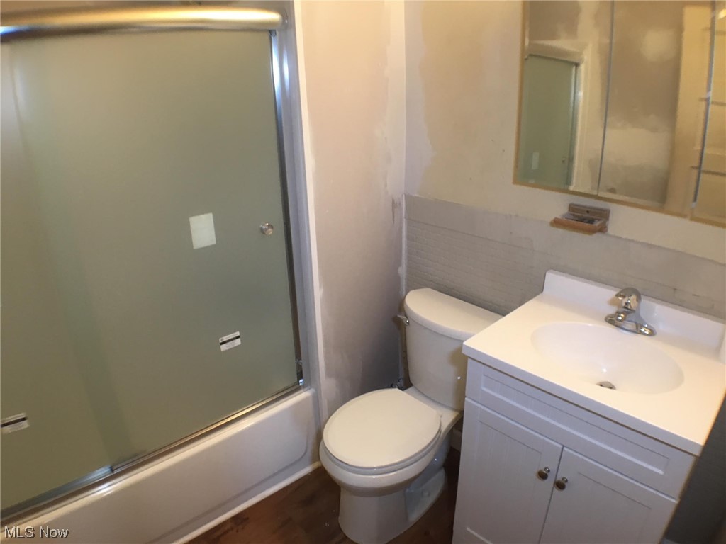 4016 Riverside Avenue Cleveland, OH 44109 - Photo 21 of 25 Full bathroom featuring combined bath / shower with glass door, toilet, hardwood / wood-style floors, and vanity with extensive cabinet space
