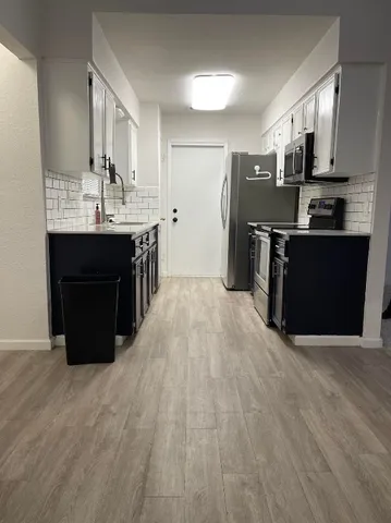 a large kitchen with stainless steel appliances granite countertop a large counter top and wooden floors