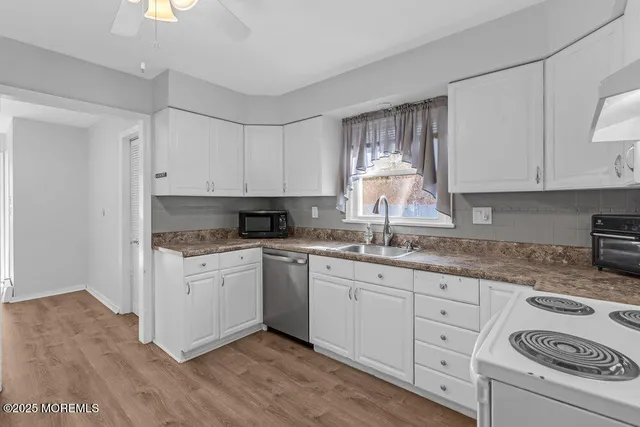 a kitchen with granite countertop white cabinets white appliances a sink and a stove