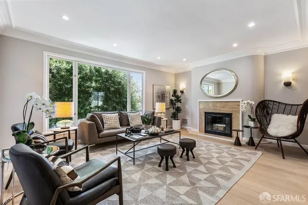 a living room with furniture a fireplace a rug and a large window