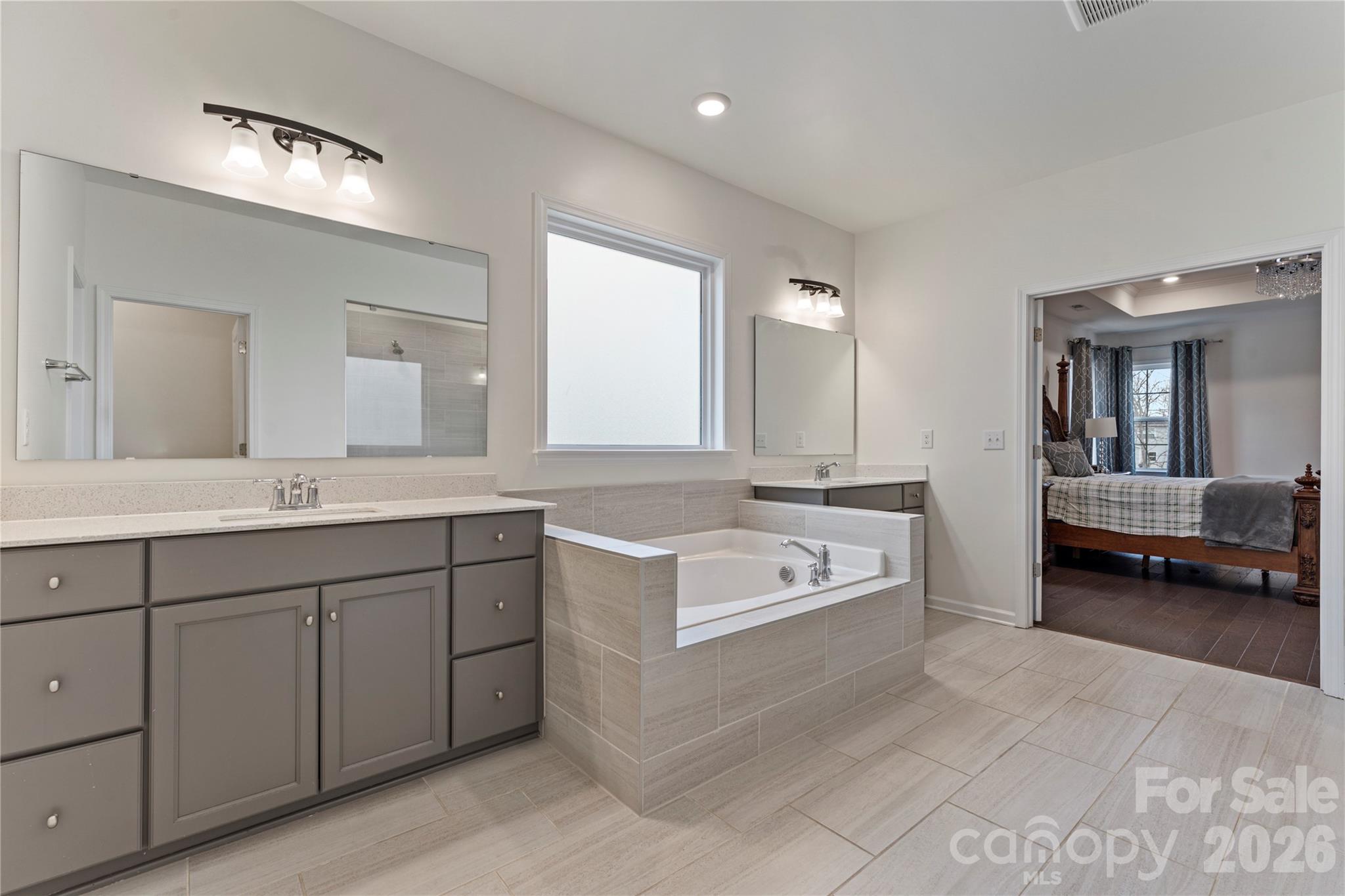 9786 Verdun Court Fort Mill, SC 29707 - Photo 20 of 41 a spacious bathroom with a double vanity sink large mirror and a bathtub