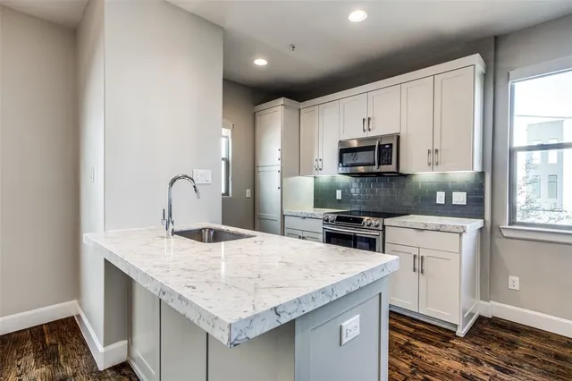 a kitchen with granite countertop a stove sink and microwave