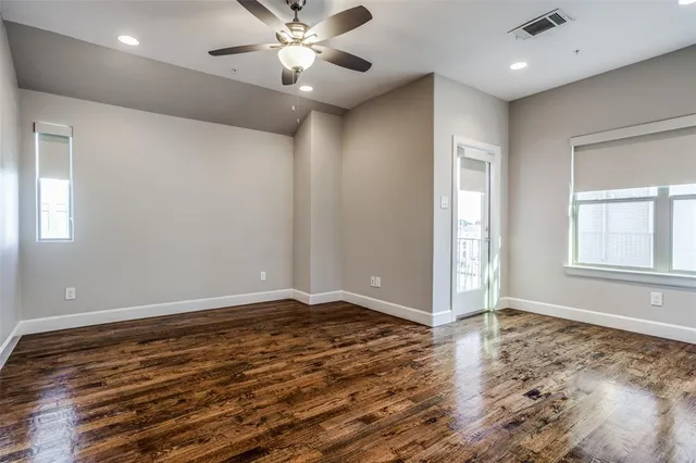 a view of an empty room with window and wooden floor