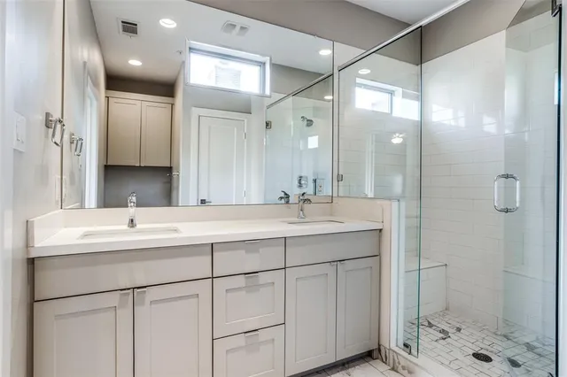 a bathroom with a double vanity sink mirror and shower