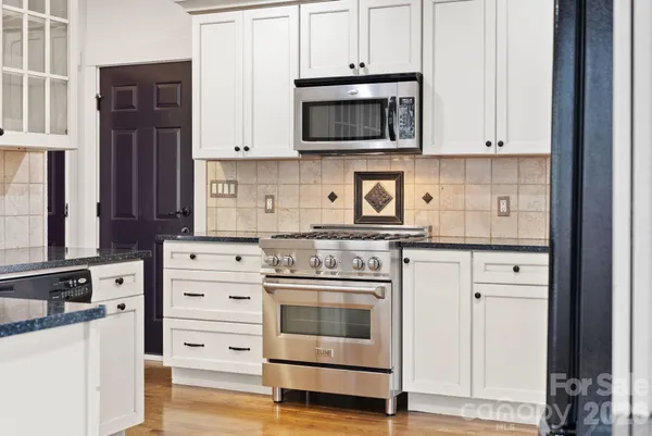 a kitchen with stainless steel appliances granite countertop a stove microwave and cabinets