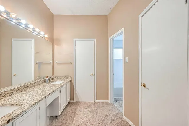 a bathroom with a granite countertop sink a mirror and shower