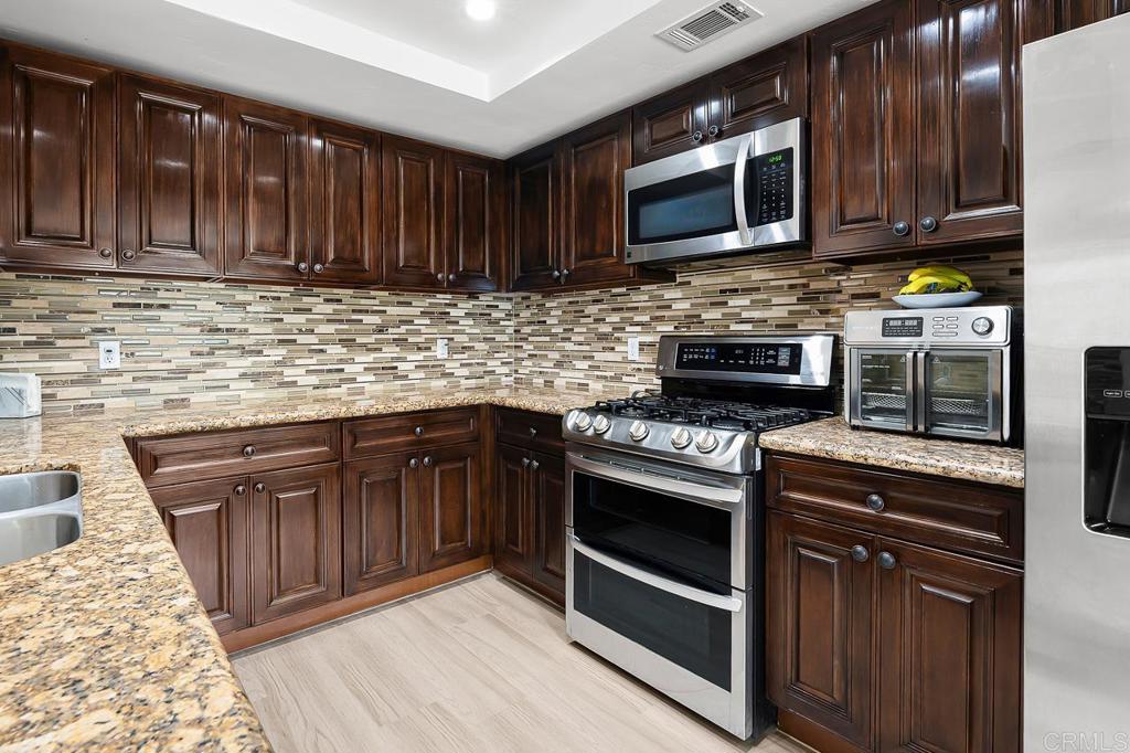 1661 Grove Road El Cajon, CA 92020 - Photo 3 of 44 a kitchen with granite countertop wood cabinets stainless steel appliances and a sink