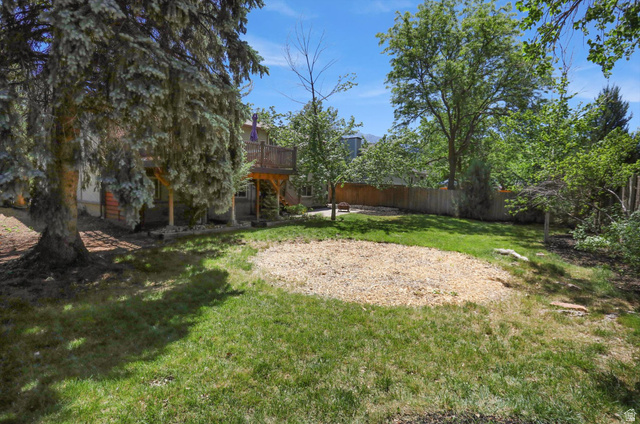 8938 Manchester Lane Sandy, UT 84093 - Photo 41 of 50 Expansive backyard featuring a large grass area, a dedicated wood chip zone, mature trees, and a wooden privacy fence