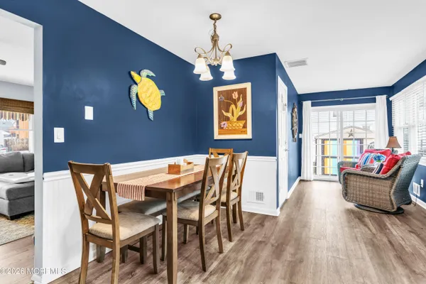 a dining room with furniture a chandelier and wooden floor