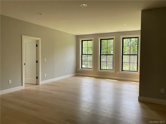 a view of an empty room with glass door and wooden floor