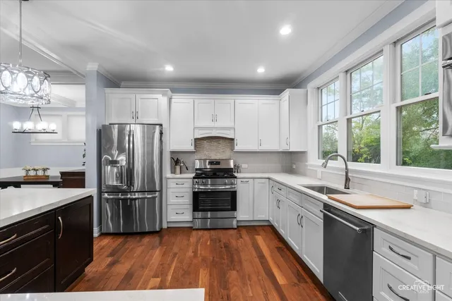 a kitchen with a refrigerator a sink and white cabinets