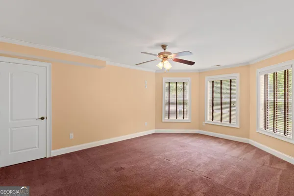 a view of an empty room with wooden floor and a ceiling fan