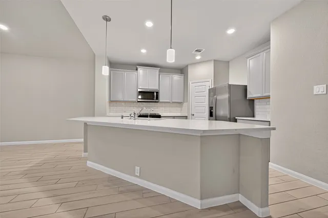 a kitchen with stainless steel appliances granite countertop a sink a stove a refrigerator and white cabinets