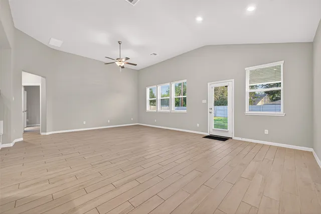 a view of an empty room with a window and wooden floor
