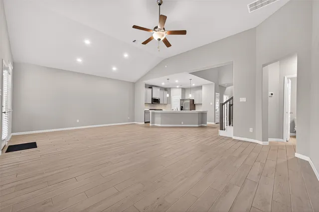 a view of a livingroom with a ceiling fan wooden floor and a ceiling fan