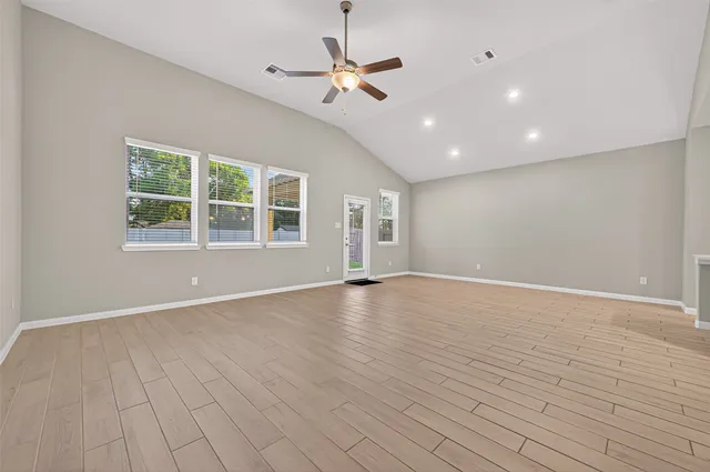 a view of an empty room with a window and wooden floor