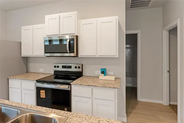 a kitchen with stainless steel appliances granite countertop a stove microwave and sink