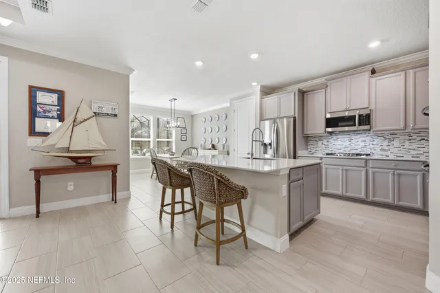 a kitchen with kitchen island granite countertop a stove top oven a sink dishwasher a dining table and chairs with wooden floor