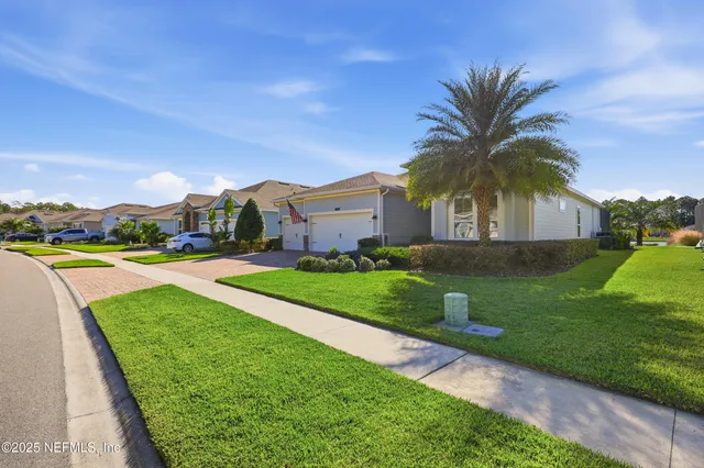 a view of a house with a big yard potted plants and palm trees