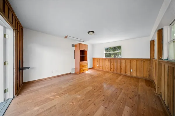 a view of an empty room with wooden floor and a window