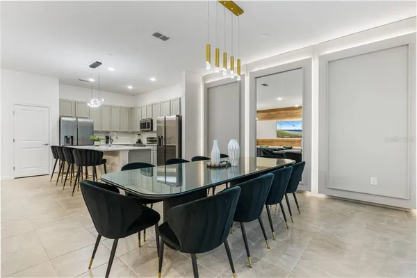 a dining room with stainless steel appliances kitchen island granite countertop a dining table chairs and a refrigerator