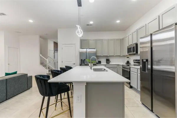 a kitchen with stainless steel appliances kitchen island a table chairs microwave and refrigerator