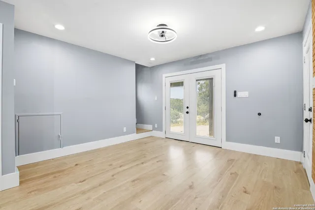 a view of an empty room with wooden floor and windows