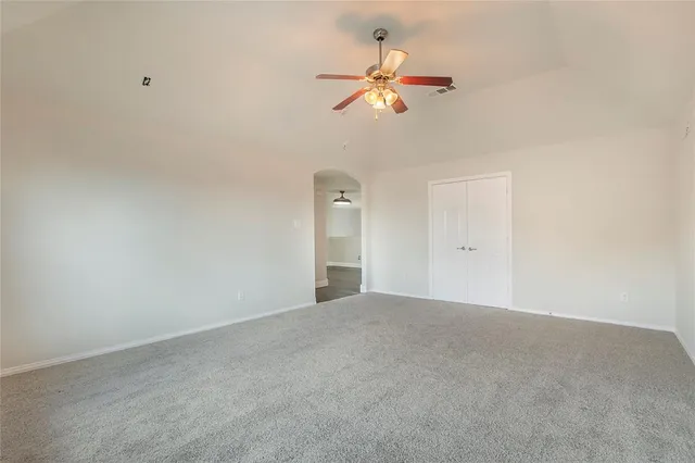 a view of an empty room with chandelier fan