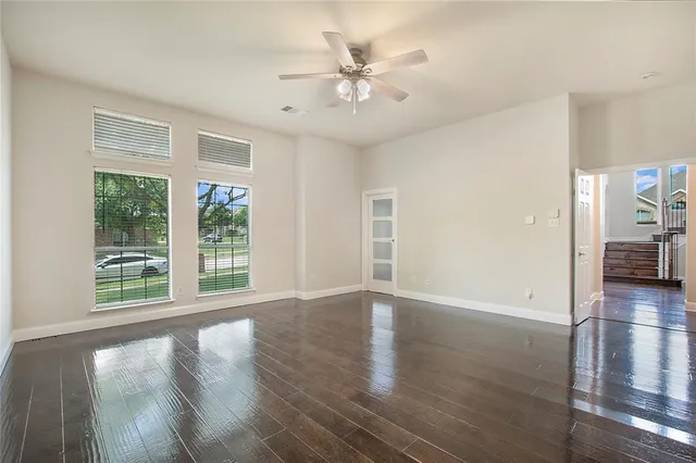 a view of an empty room with window and wooden floor