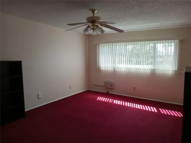 en empty room with windows and ceiling fan