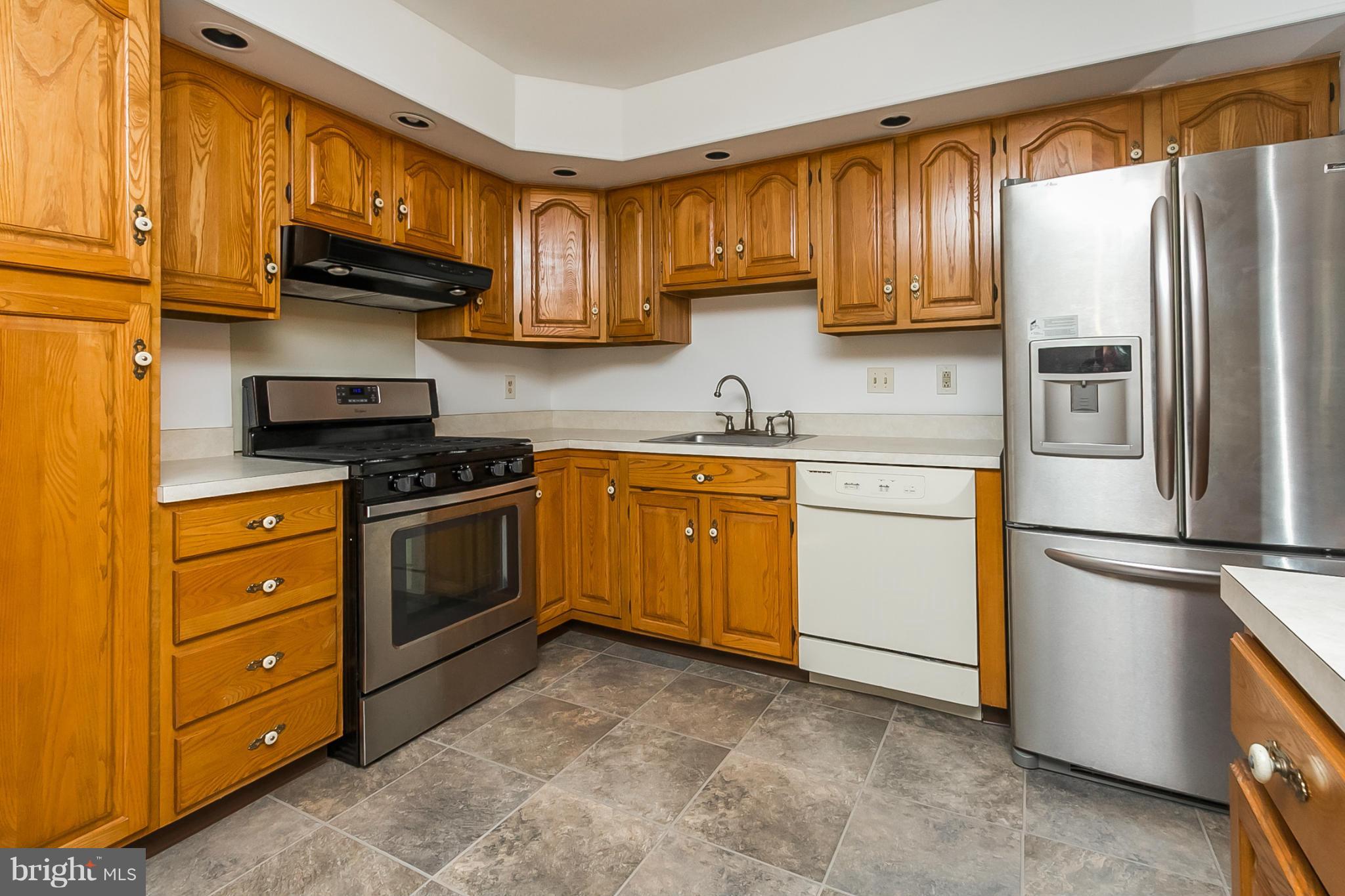 4241 4 Mills Road Baltimore, MD 21236 - Photo 7 of 25 a kitchen with stainless steel appliances granite countertop a refrigerator stove and sink with wooden cabinets