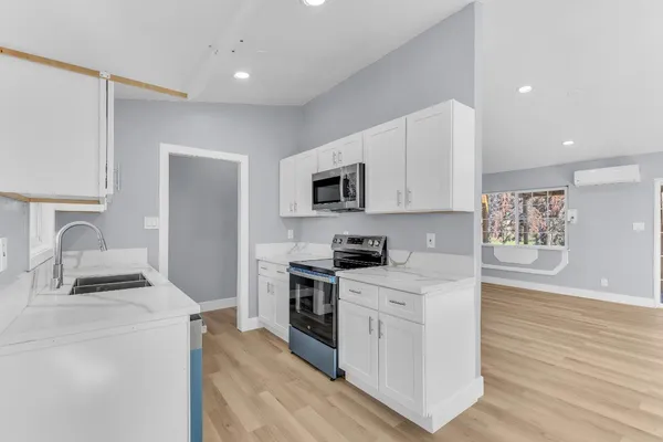 a kitchen with granite countertop a stove top oven a sink dishwasher and a refrigerator with wooden floor