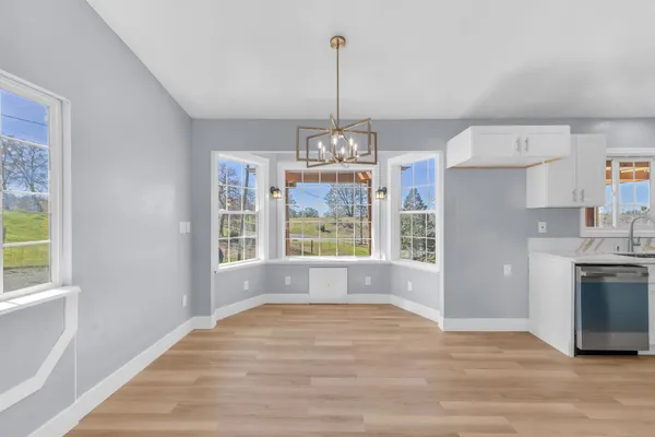 a view of an empty room with window and wooden floor