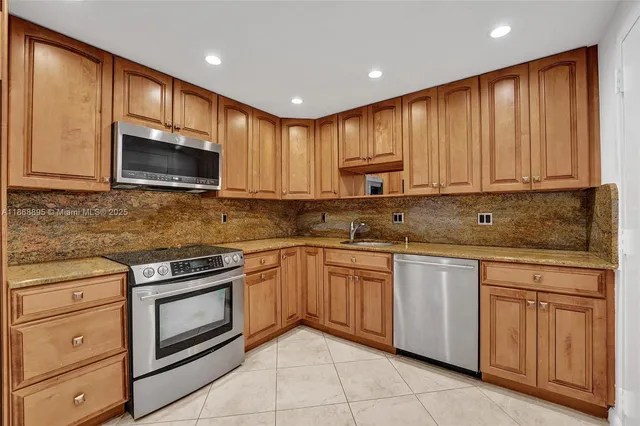 a kitchen with granite countertop wooden cabinets stainless steel appliances and a window