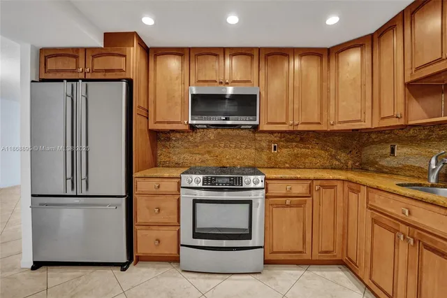 a kitchen with granite countertop a refrigerator stove and cabinets