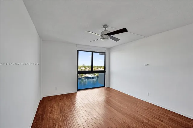 a view of empty room with wooden floor and fan