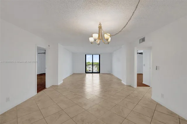 wooden floor in an empty room with a chandelier fan