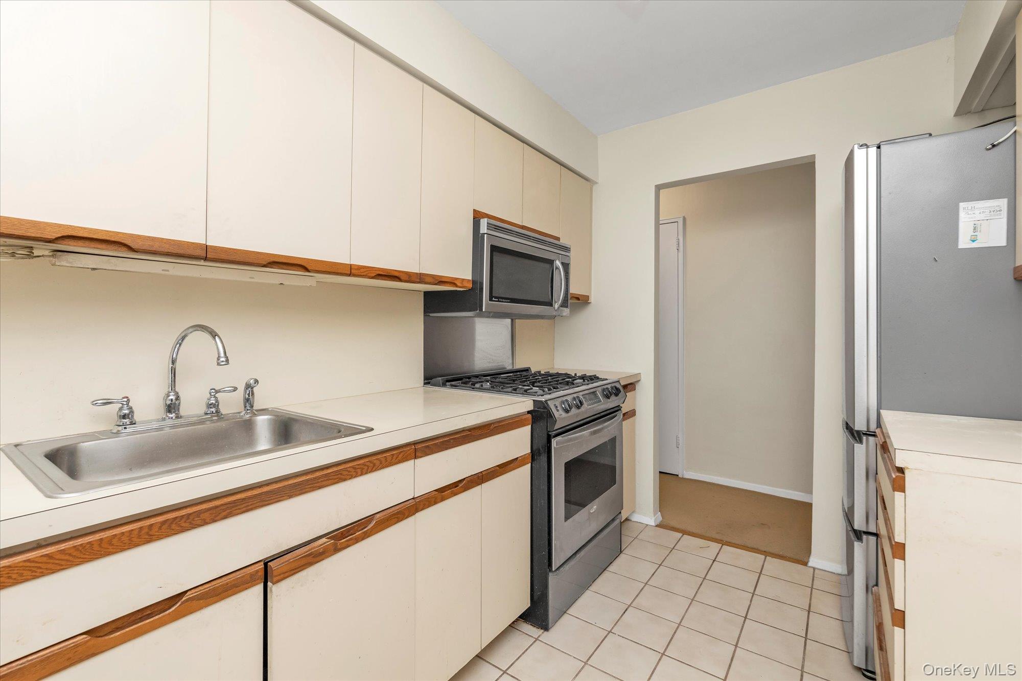 30 Pearsall Avenue, Unit 2F Glen Cove, NY 11542 - Photo 11 of 25 Kitchen with stainless steel appliances, light countertops, light tile patterned floors, and white cabinets