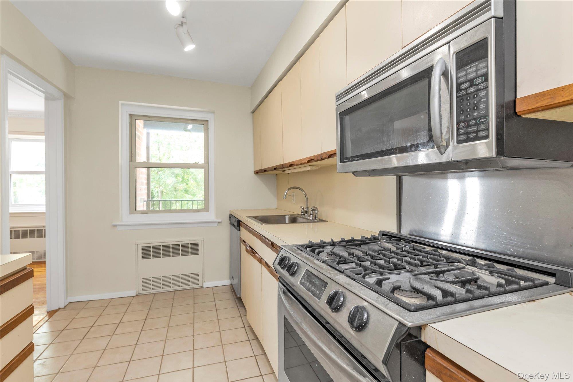 30 Pearsall Avenue, Unit 2F Glen Cove, NY 11542 - Photo 12 of 25 Kitchen with appliances with stainless steel finishes, light countertops, light tile patterned floors, and radiator